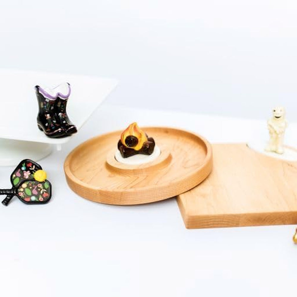 Assorted seasonal mini figurines, including a campfire, boots, and a ghost, arranged on wooden trays.