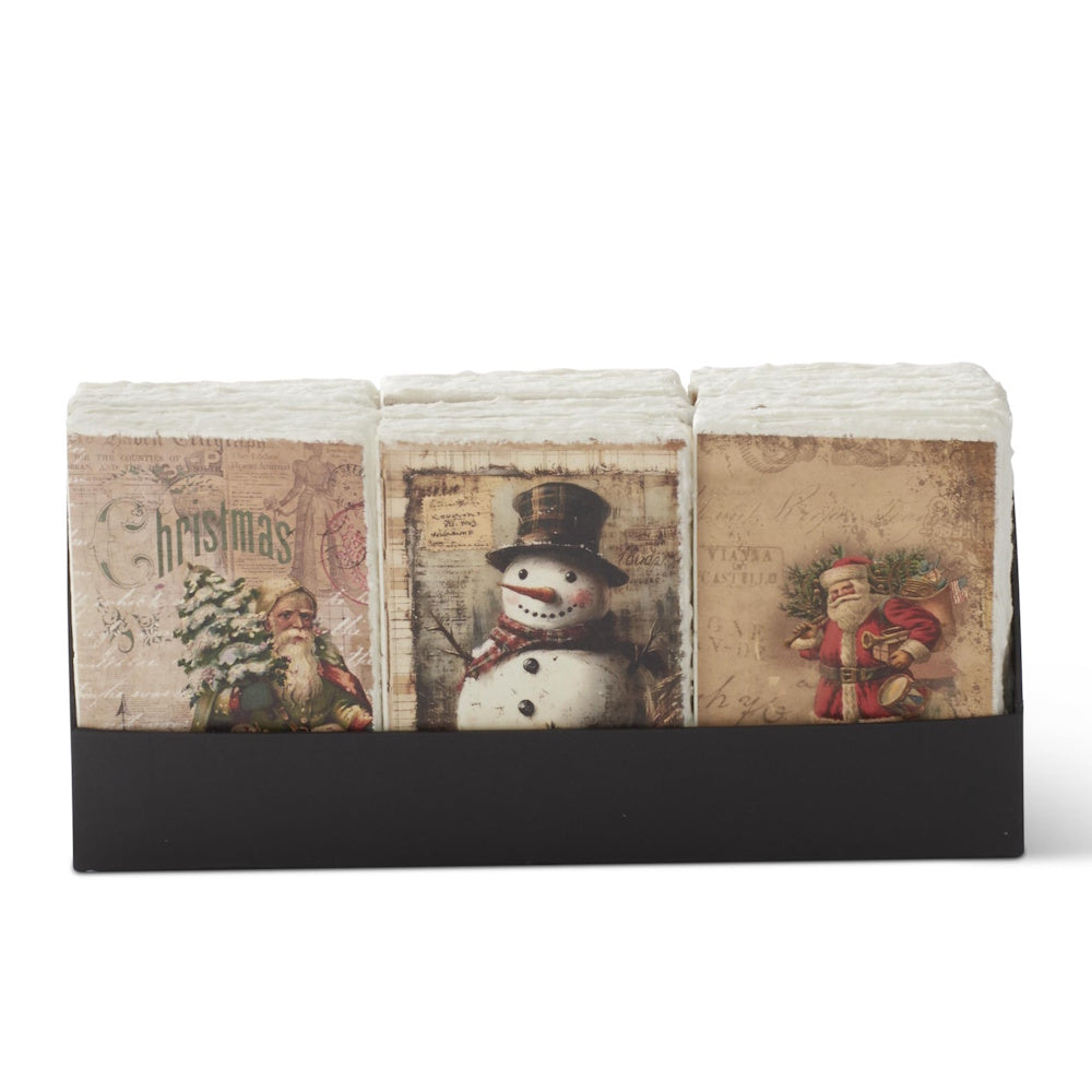 A front-facing view of a black display holder filled with assorted soft-cover Christmas journals featuring vintage illustrations and deckle edges.