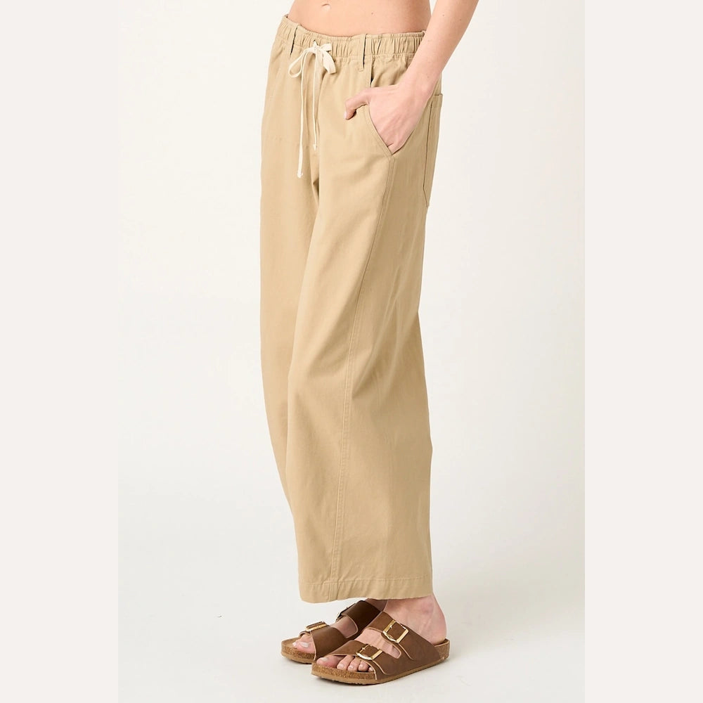 Wide-leg khaki drawstring pants with an elastic waist, paired with brown double-strap sandals on a white background.