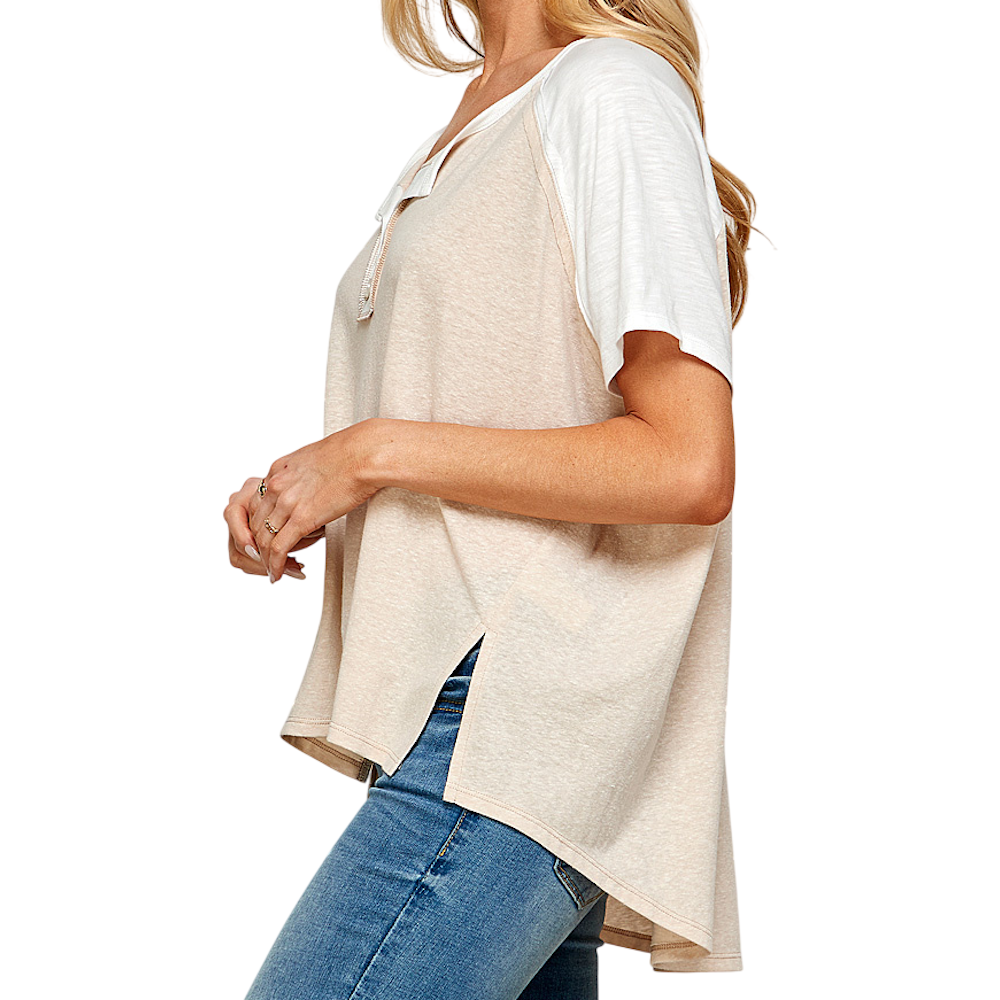 Side view of a person wearing a beige and white short-sleeve henley shirt with blue jeans.