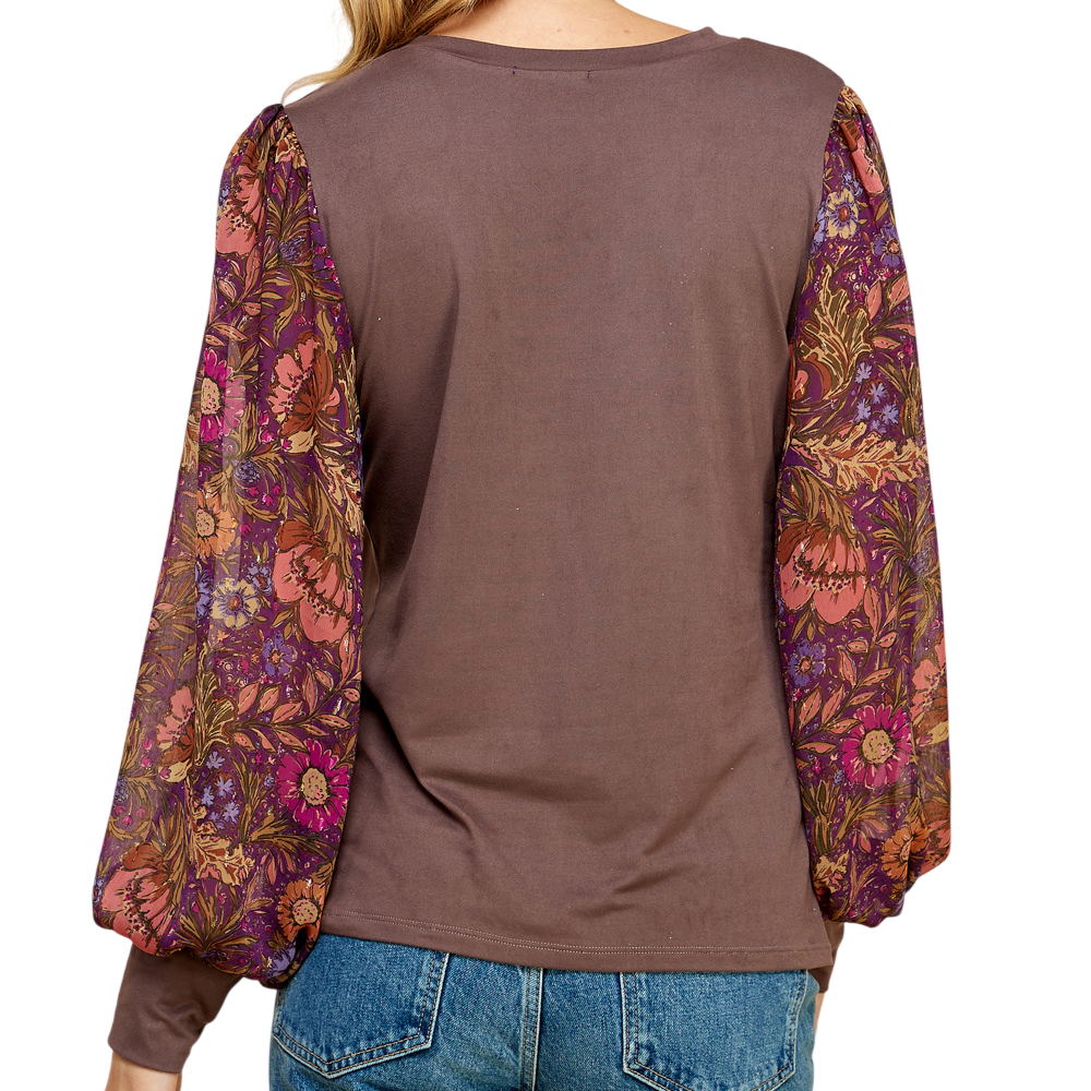 Back view of a woman wearing a brown long-sleeve top with colorful, printed floral balloon sleeves.