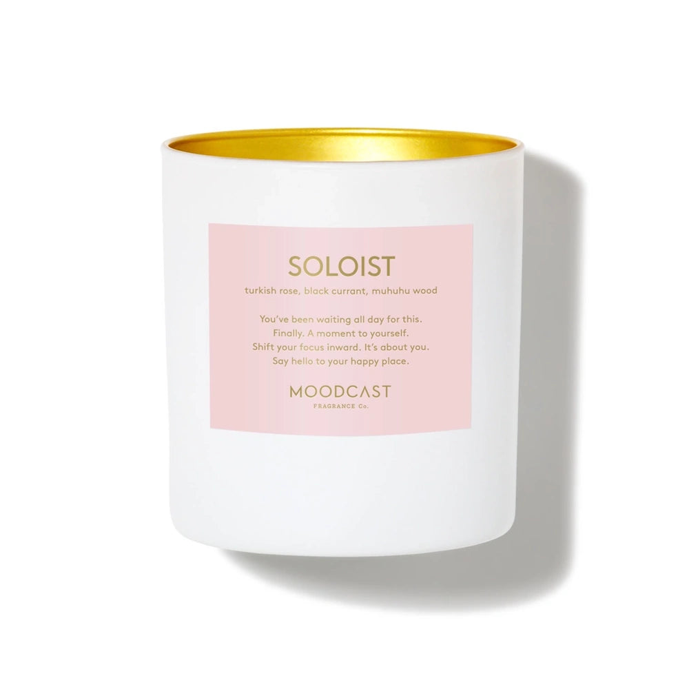 White Moodcast "Soloist" candle with a gold interior rim and pink label on a white background.