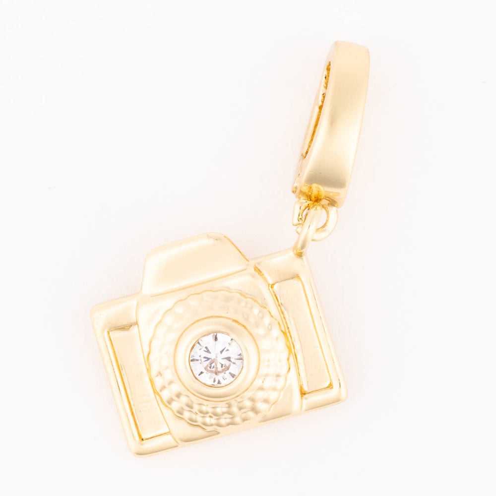 Gold camera charm with a sparkling crystal lens on a white background.