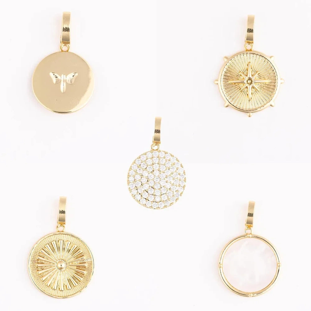 Five gold charm pendants with varied designs, including starburst, pavé, and moth motifs.