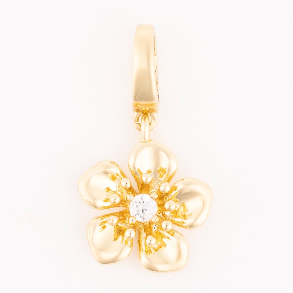 Gold hibiscus flower charm centered with a clear sparkling crystal hanging from a smooth bail.