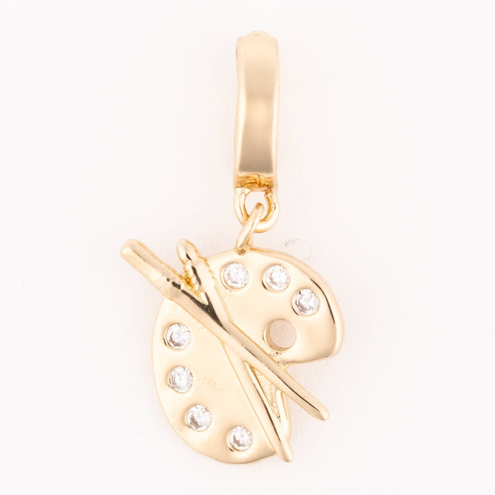 Gold artist palette charm featuring small crystal accents and crossed paintbrushes.