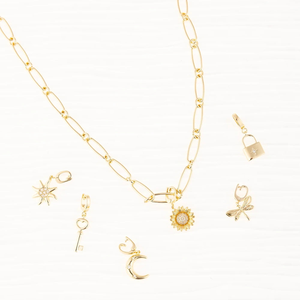 Gold link chain necklace with a sunflower charm, surrounded by key, moon, and sun charms on white background.