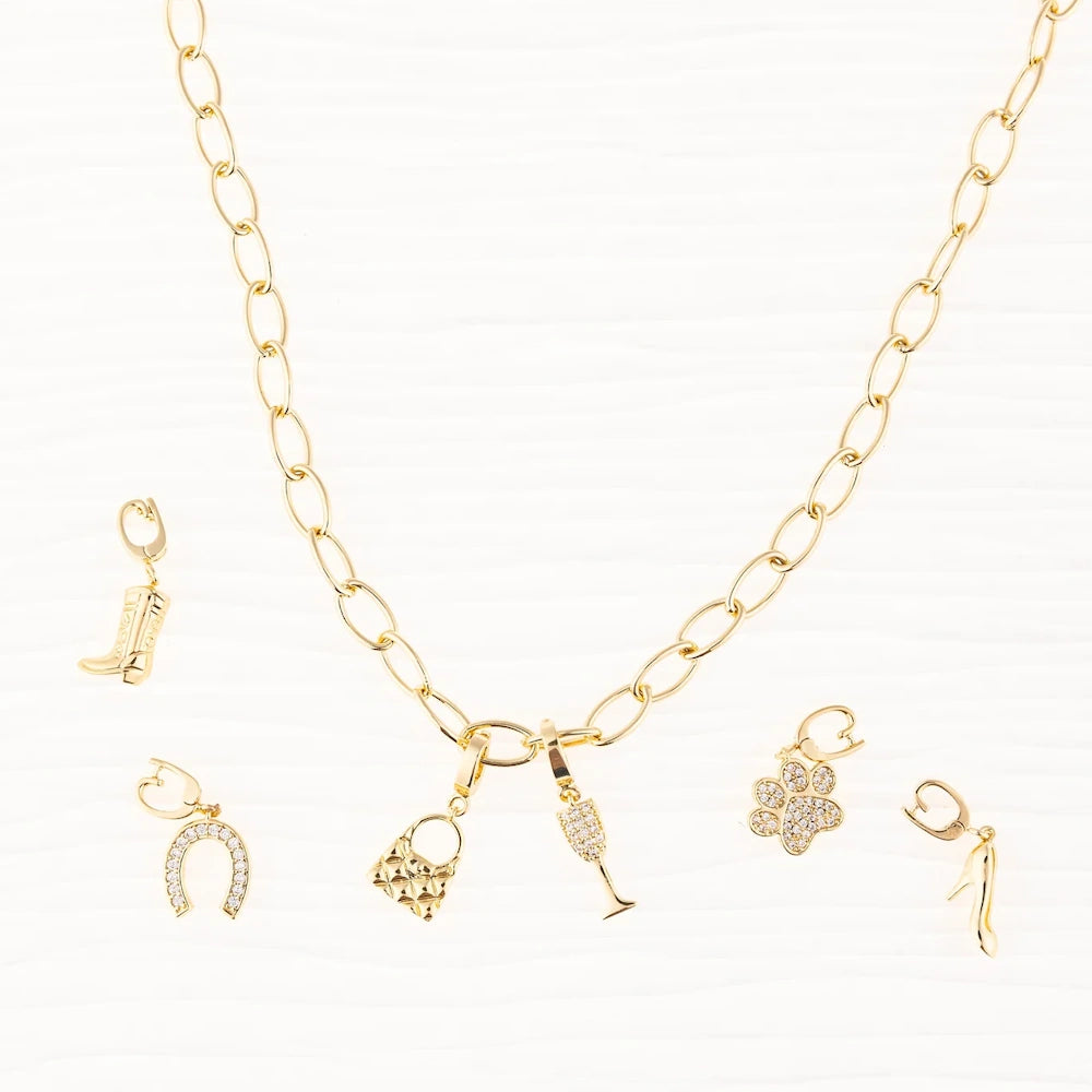 Gold link chain necklace with handbag and champagne charms, surrounded by boot, paw, and shoe charms.