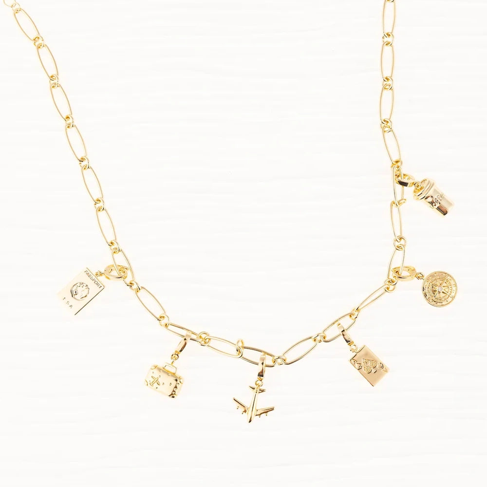 Gold link chain charm necklace featuring travel-themed charms like an airplane, suitcase, and passport.