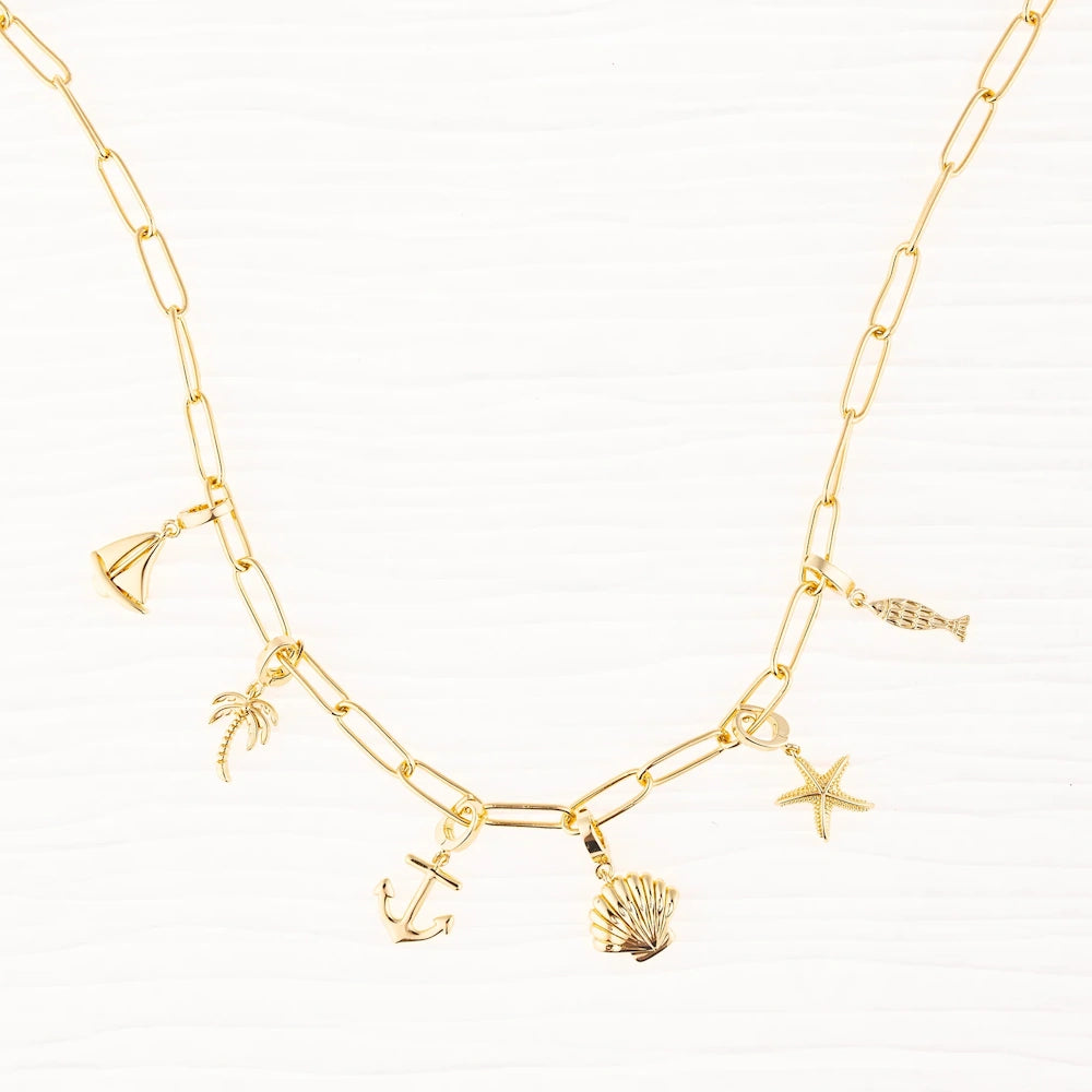 Gold link chain charm necklace featuring beach and ocean charms like a sailboat, anchor, and seashell.
