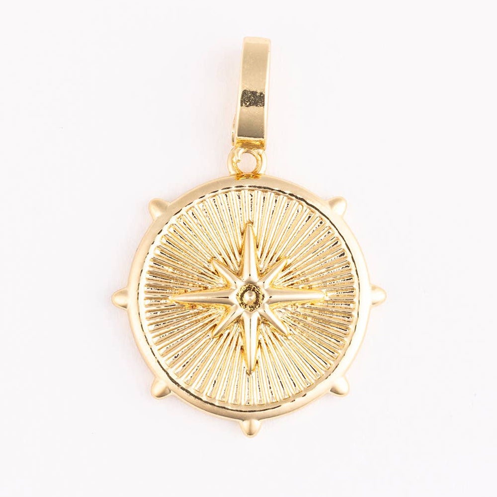 Gold north star compass pendant necklace charm with celestial sunburst design on a white background.