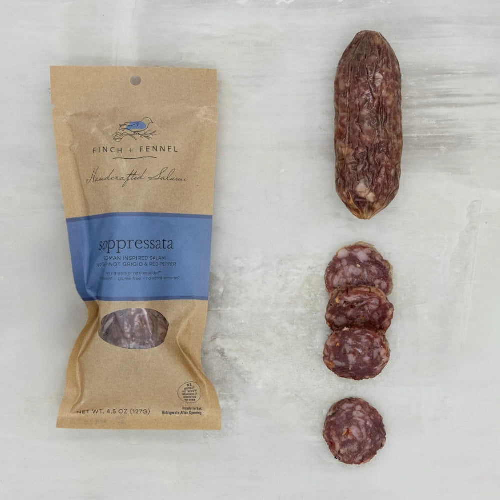 Finch + Fennel Soppressata salumi packaging next to a whole dry-cured sausage and several round, marbled slices.