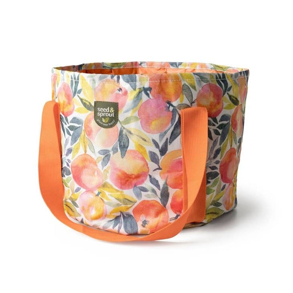 A fabric garden bag featuring a peach pattern and orange handles on a white background.