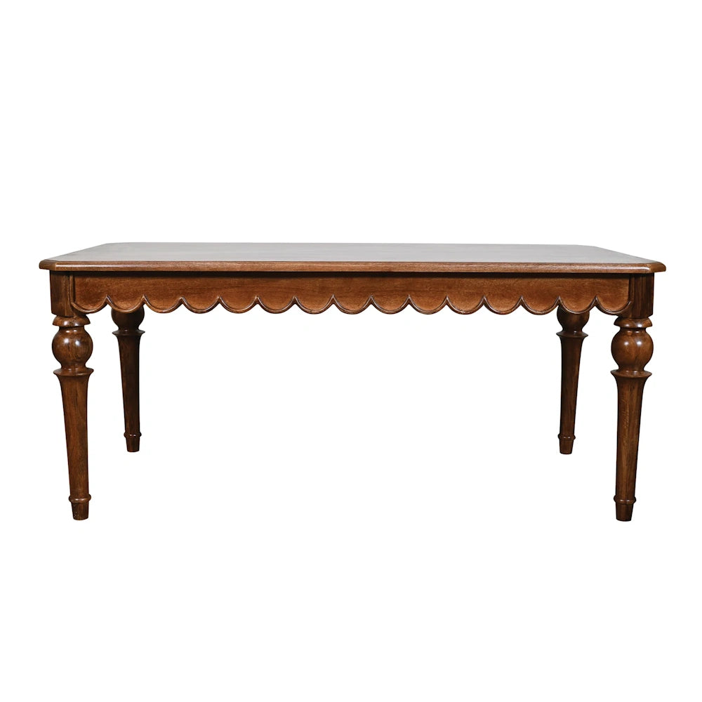 Traditional dark wood dining table with scalloped apron detail and turned legs on white background.