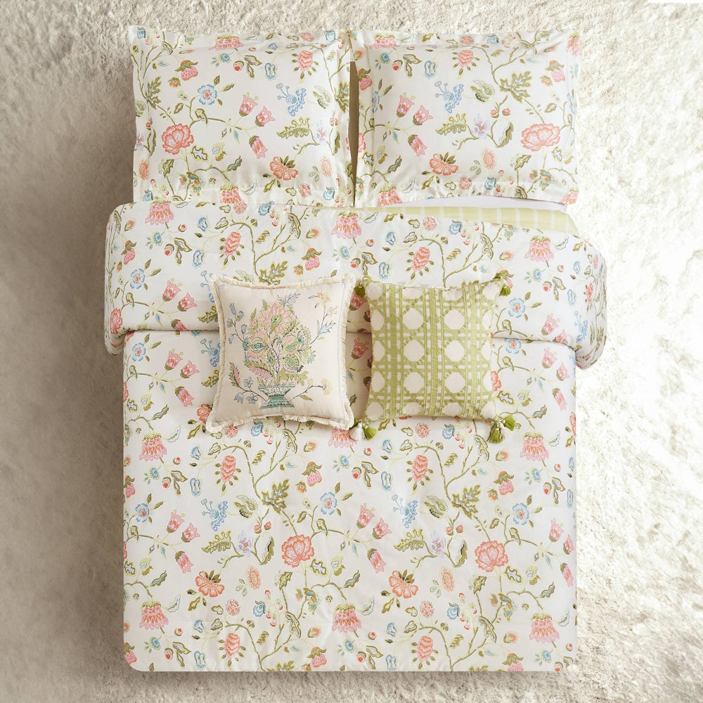 White bedding set with pink and blue floral patterns, featuring matching pillow shams and decorative cushions.