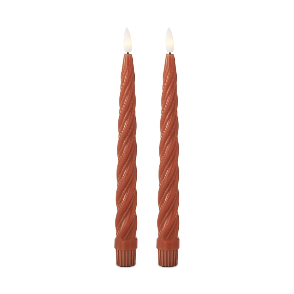 A pair of terracotta-colored spiral LED taper candles with lit flames on a white background.