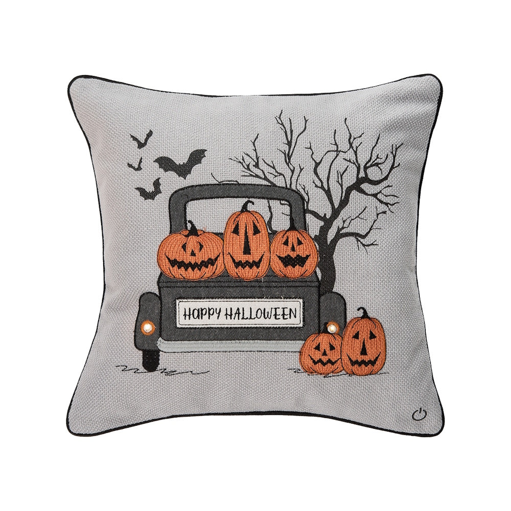 Gray Halloween throw pillow featuring a truck filled with pumpkins and LED lights on the headlights.