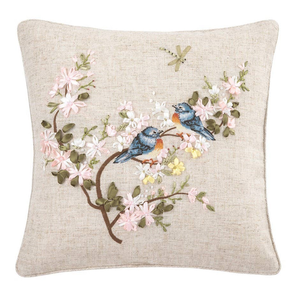 Square linen pillow with ribbon embroidery of two bluebirds on a flowering branch and a dragonfly.