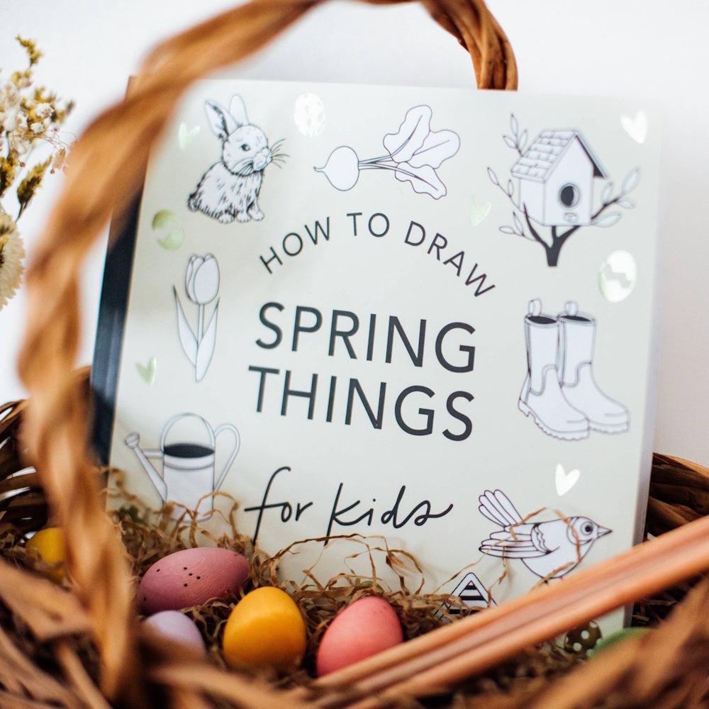 How to Draw Spring Things for Kids book in a wicker Easter basket with colorful eggs and spring illustrations.