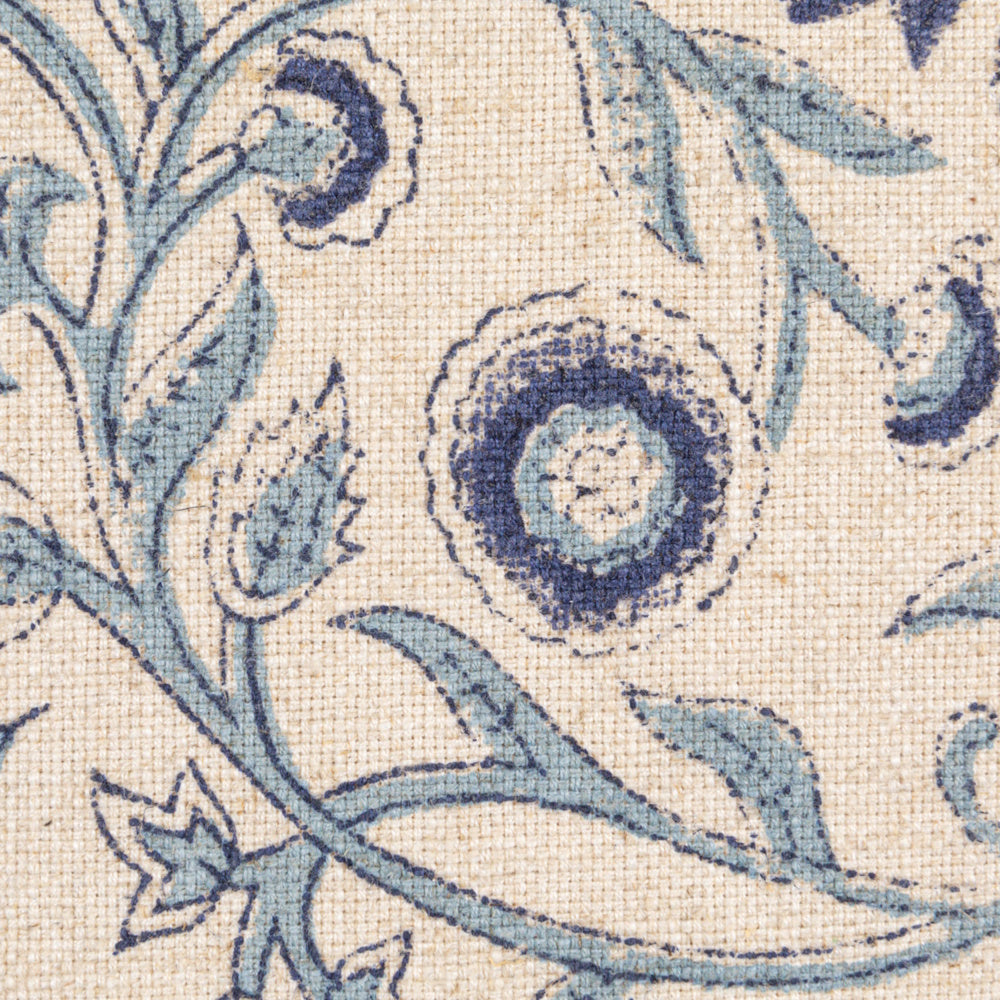 Close-up of a beige cotton-blend fabric with a block-printed blue floral and vine pattern.