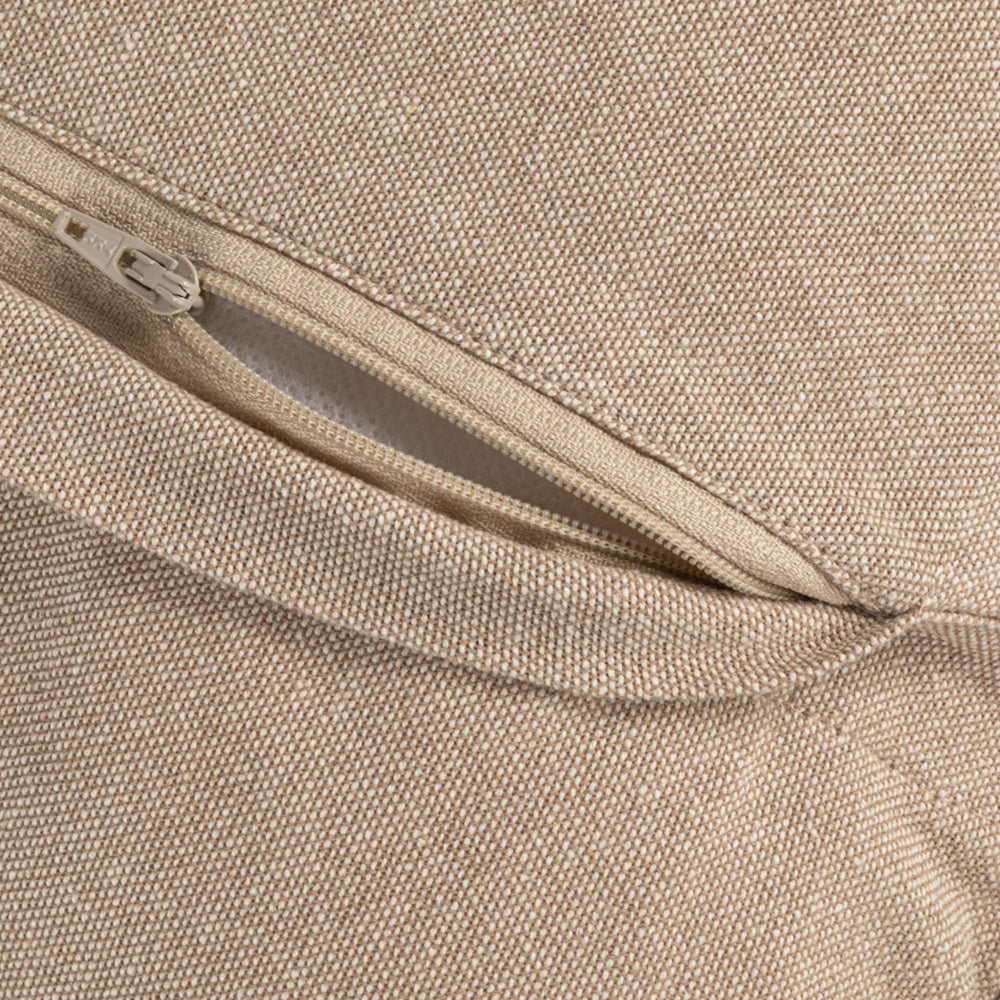 Close-up of a beige, textured fabric pillow cover featuring a hidden zipper closure slightly pulled open.