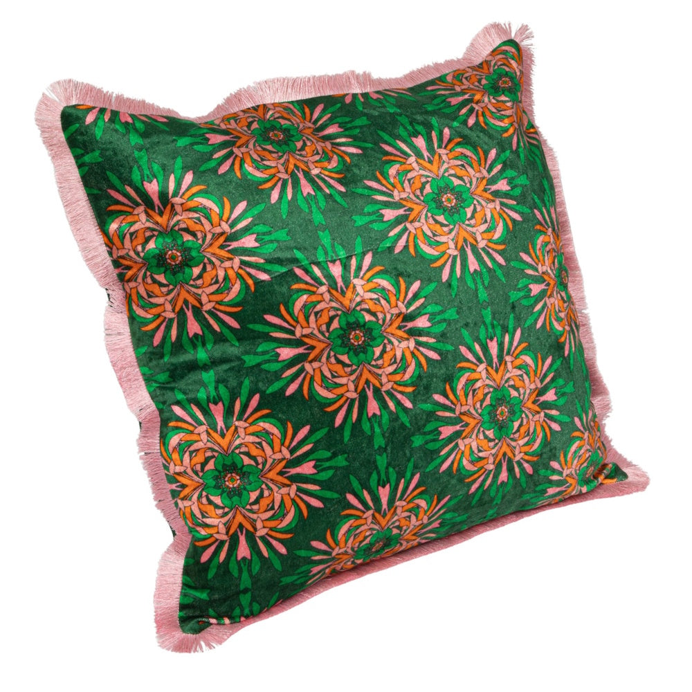Square green velvet pillow with a pink and orange kaleidoscopic floral pattern and light pink fringe.