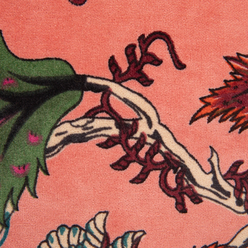 Close-up of a pink floral rug featuring intricate green leaves and white branch patterns in a plush, woven texture.