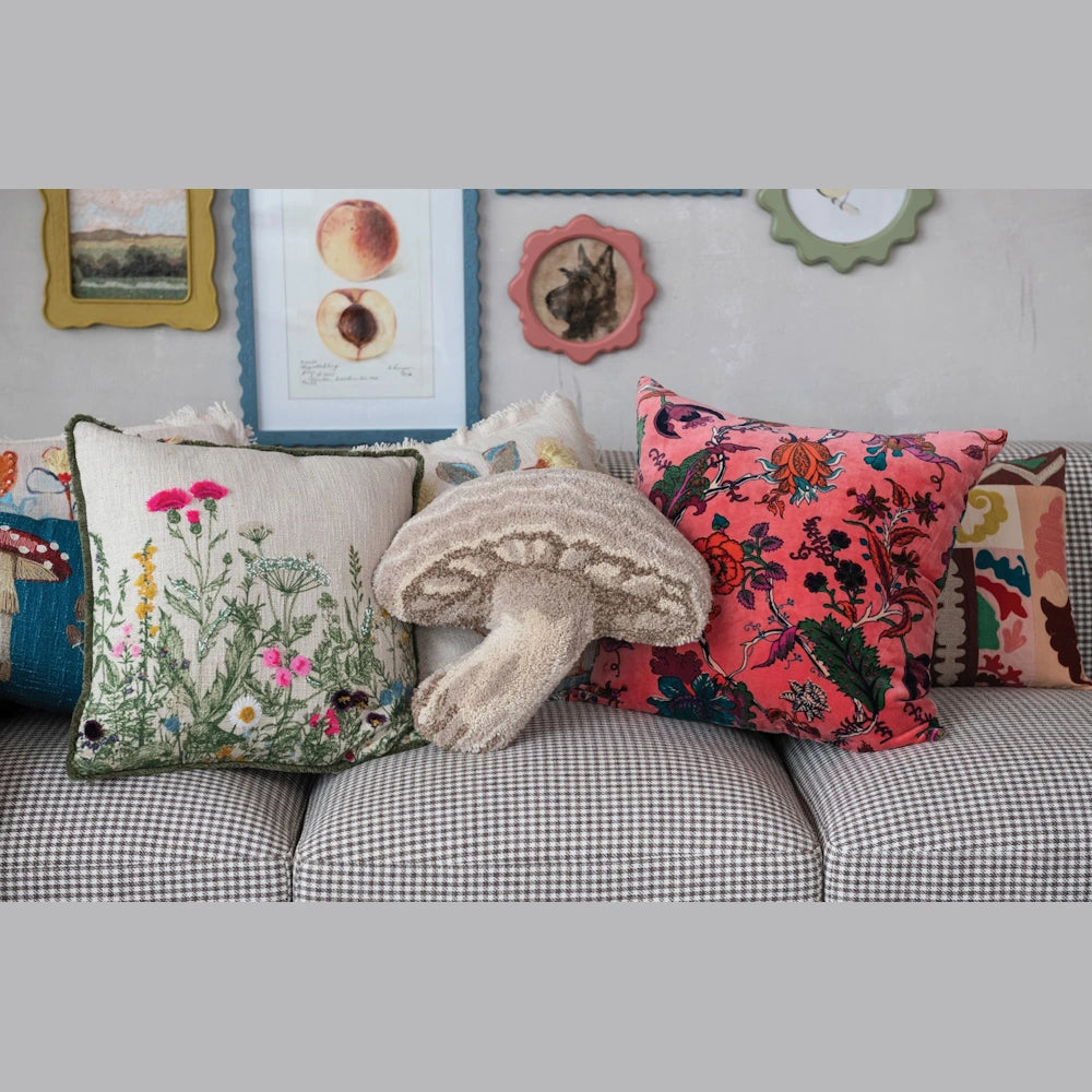 Neutral tufted mushroom shaped decorative pillow on a checkered sofa with floral embroidered cushions.
