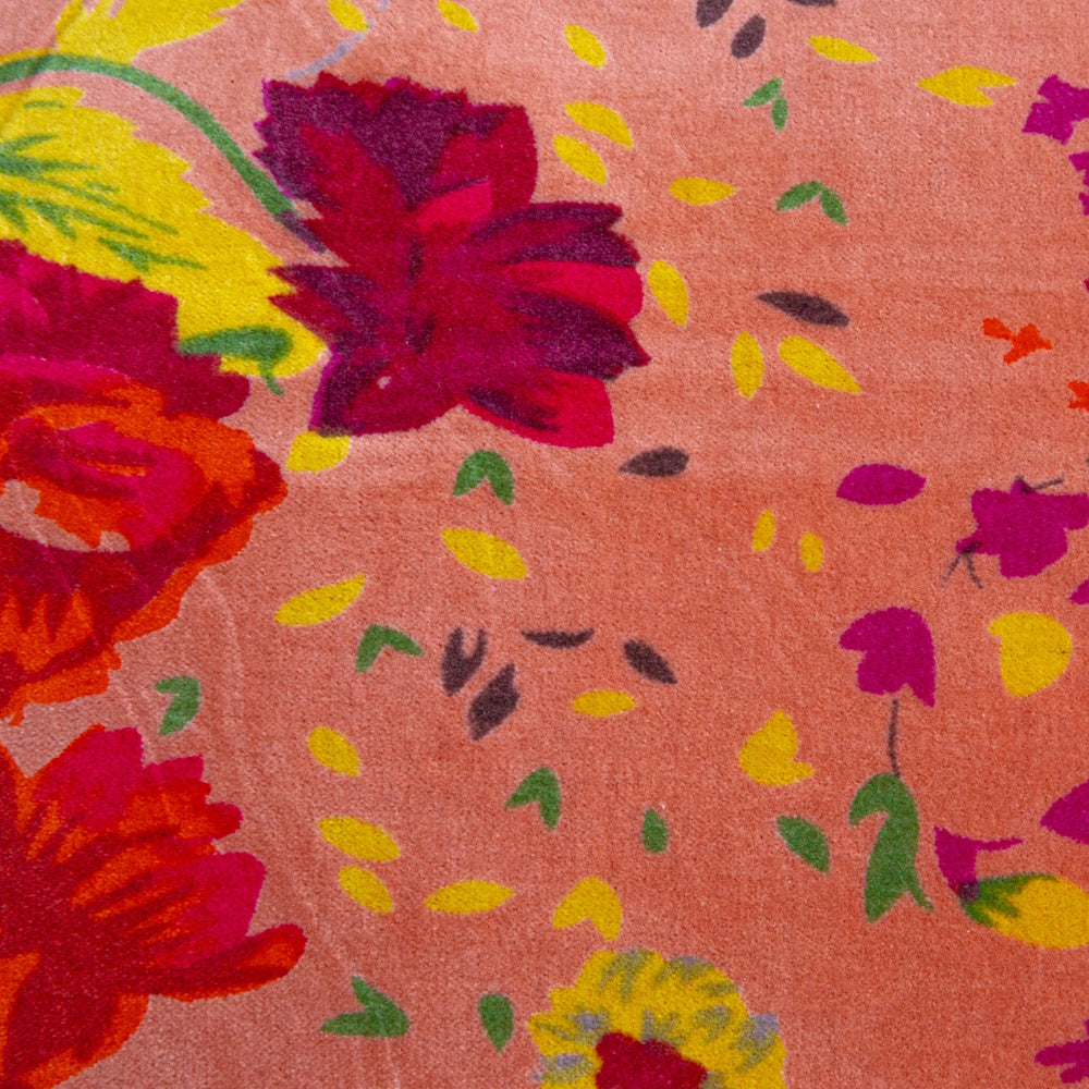Close-up of a pink cotton velvet fabric with a vibrant, colorful printed floral and leaf pattern.