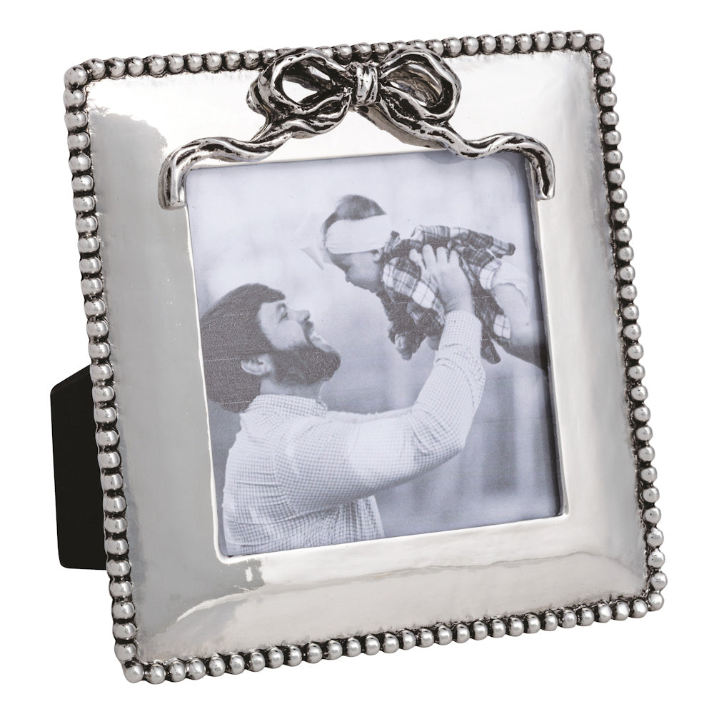 Silver mini picture frame with a beaded border and bow detail, holding a black-and-white photo of a father and baby.