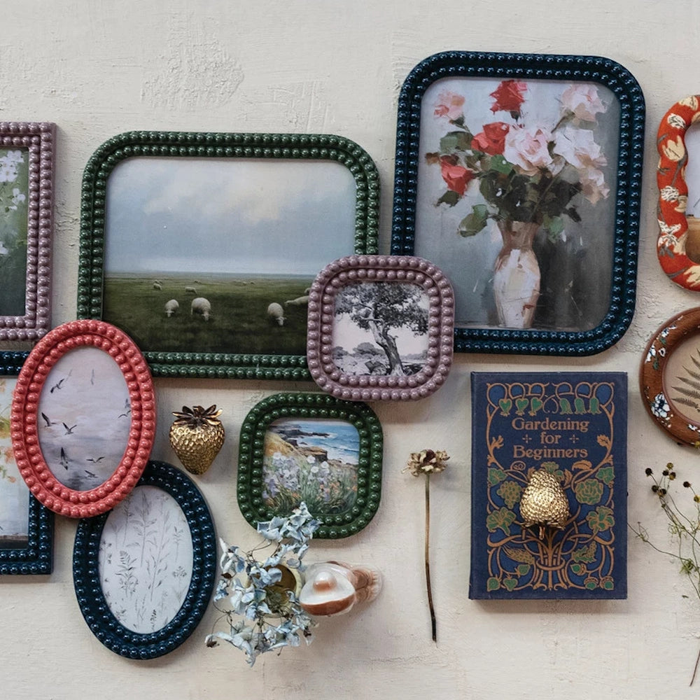 A collection of colorful bobbin-style resin photo frames in various shapes and sizes arranged on a cream-textured wall.