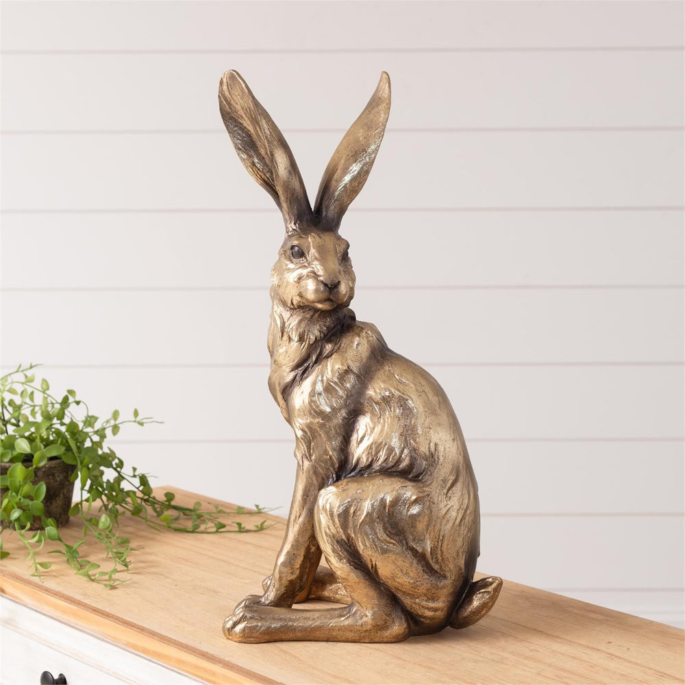 Elegant gold hare statue on a wooden shelf, rustic bronze rabbit sculpture for farmhouse mantel or shelf decor.