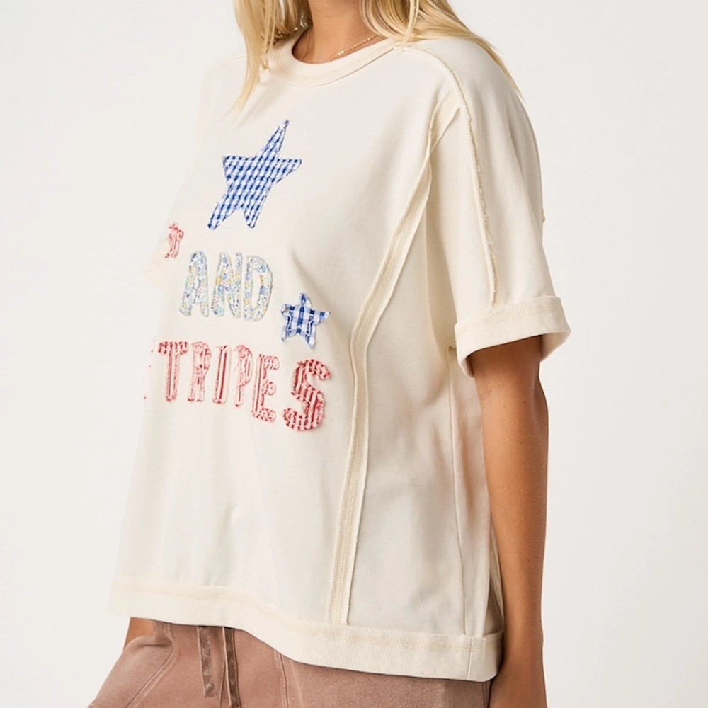 Woman wearing an off-white t-shirt with stars and text that reads "AND STRIPES".
