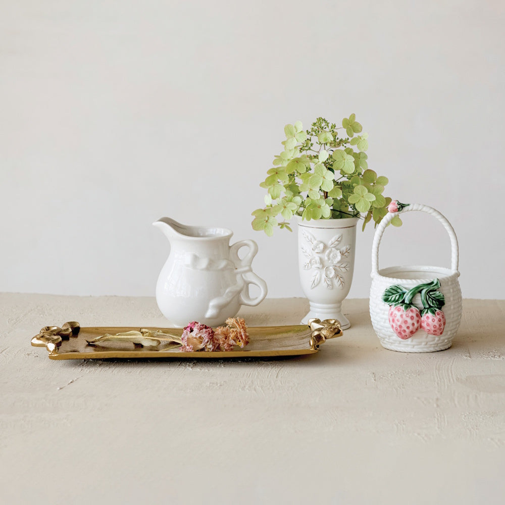 White stoneware strawberry basket, cream pitcher, and floral vase on a gold tray with dried flowers and green hydrangea.