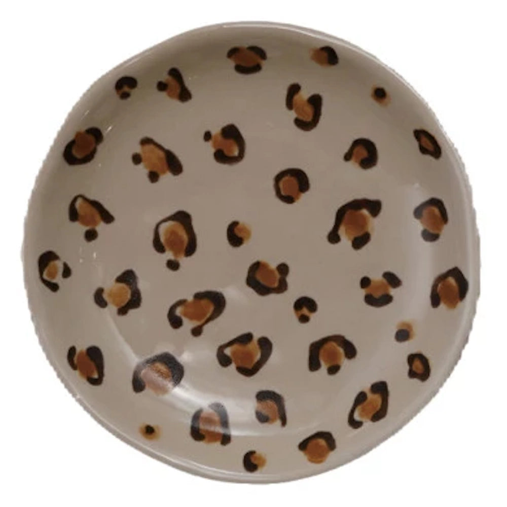 Round ceramic leopard print trinket dish with brown and black animal spots on a cream background.