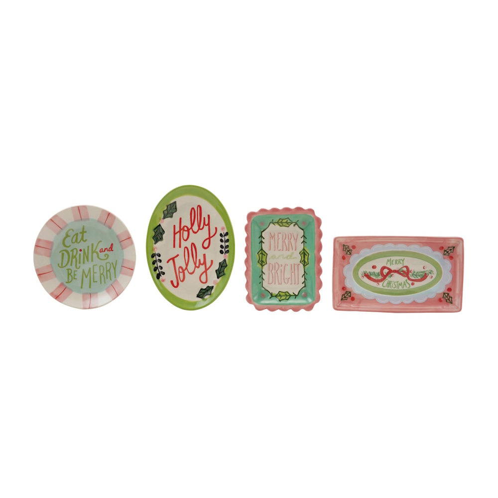 Four different stoneware dishes featuring holiday phrases and designs displayed in a row.