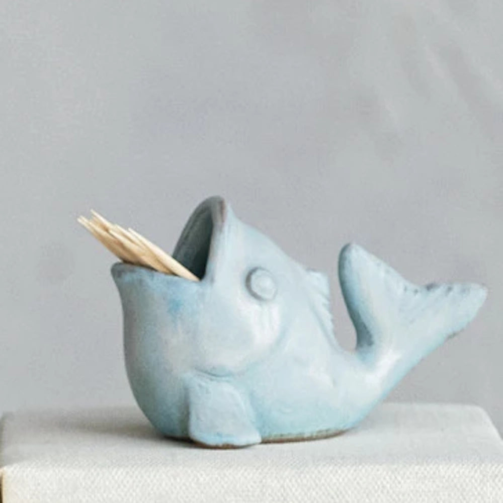 Light blue ceramic fish toothpick holder with open mouth on a white surface.