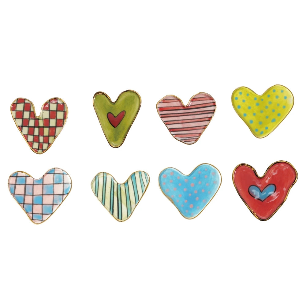 Eight colorful, patterned stoneware heart-shaped magnets with gold-rimmed edges, including stripes, dots, and checkered prints.