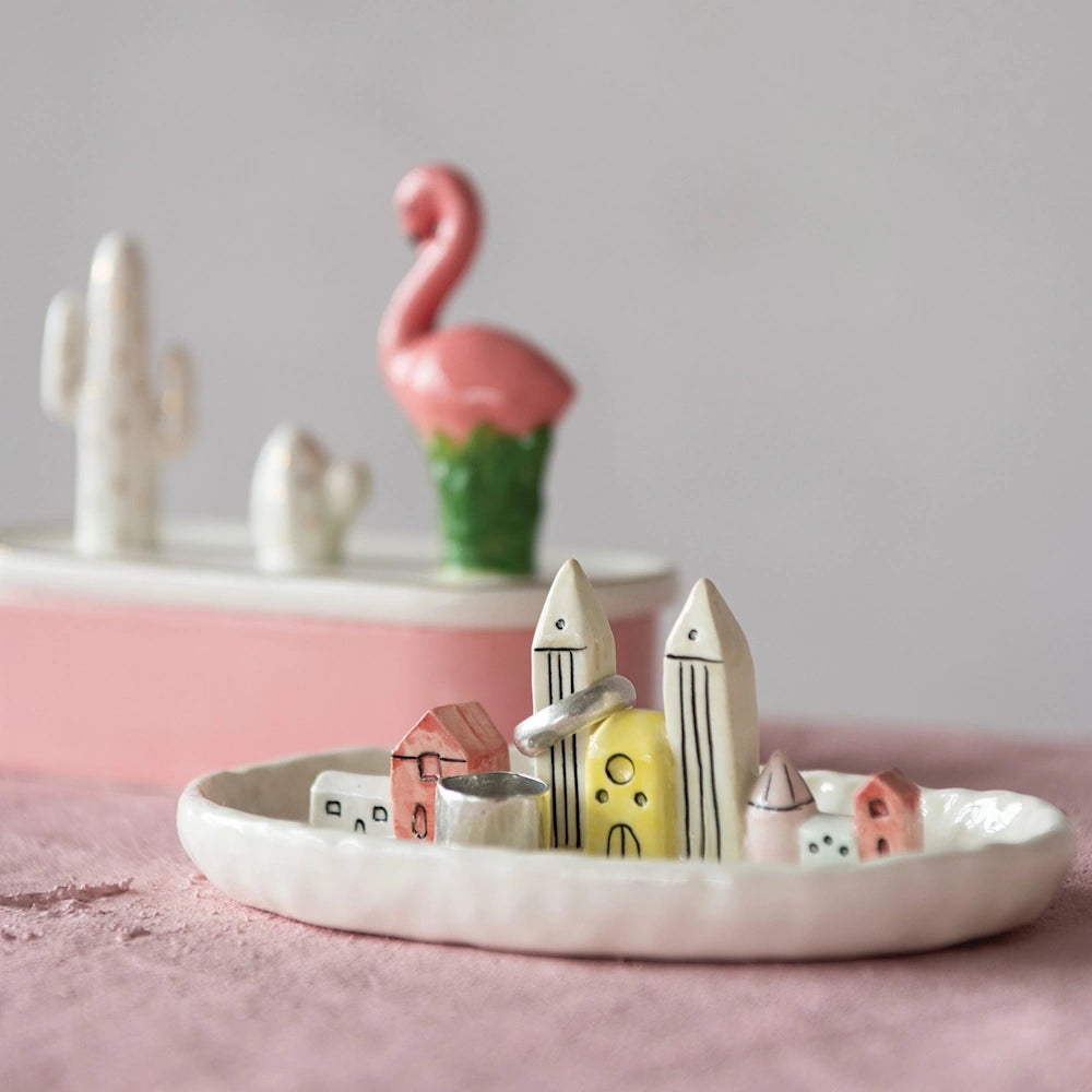 Ceramic jewelry dish featuring small painted miniature buildings holding rings inside.