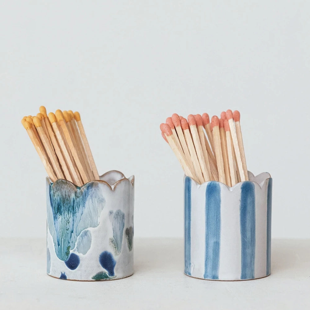 Pair of scalloped white stoneware matchstick holders filled with matches, featuring blue reactive glaze and blue stripe patterns.