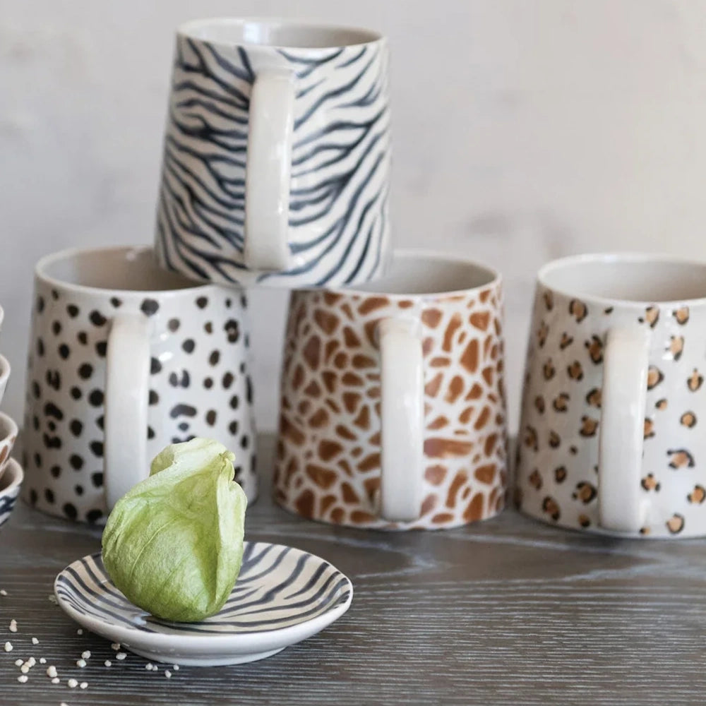 Modern animal print ceramic mugs and matching small saucer set with hand-drawn safari patterns.