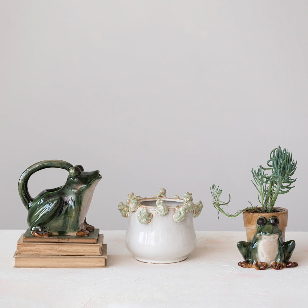 Three ceramic frog-themed planters and decor items arranged in a row against a plain light background.
