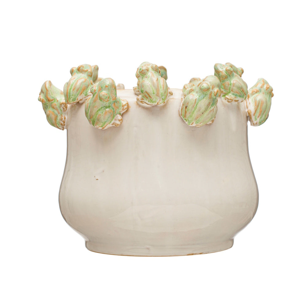 White ceramic planter with small green and orange sculpted frogs lining the upper rim against a white background.