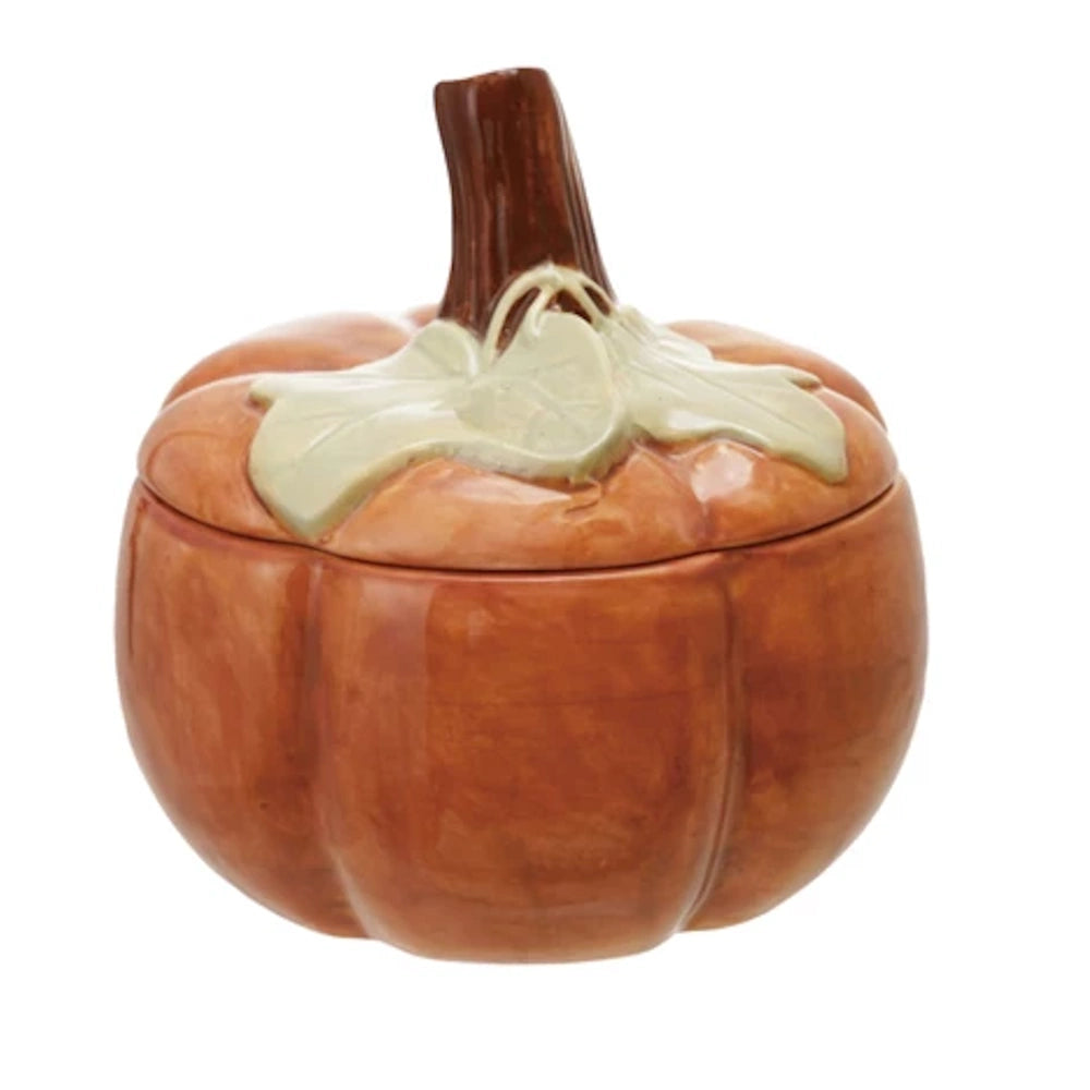 Orange stoneware pumpkin-shaped jar with a lid featuring green leaves and a brown stem handle.