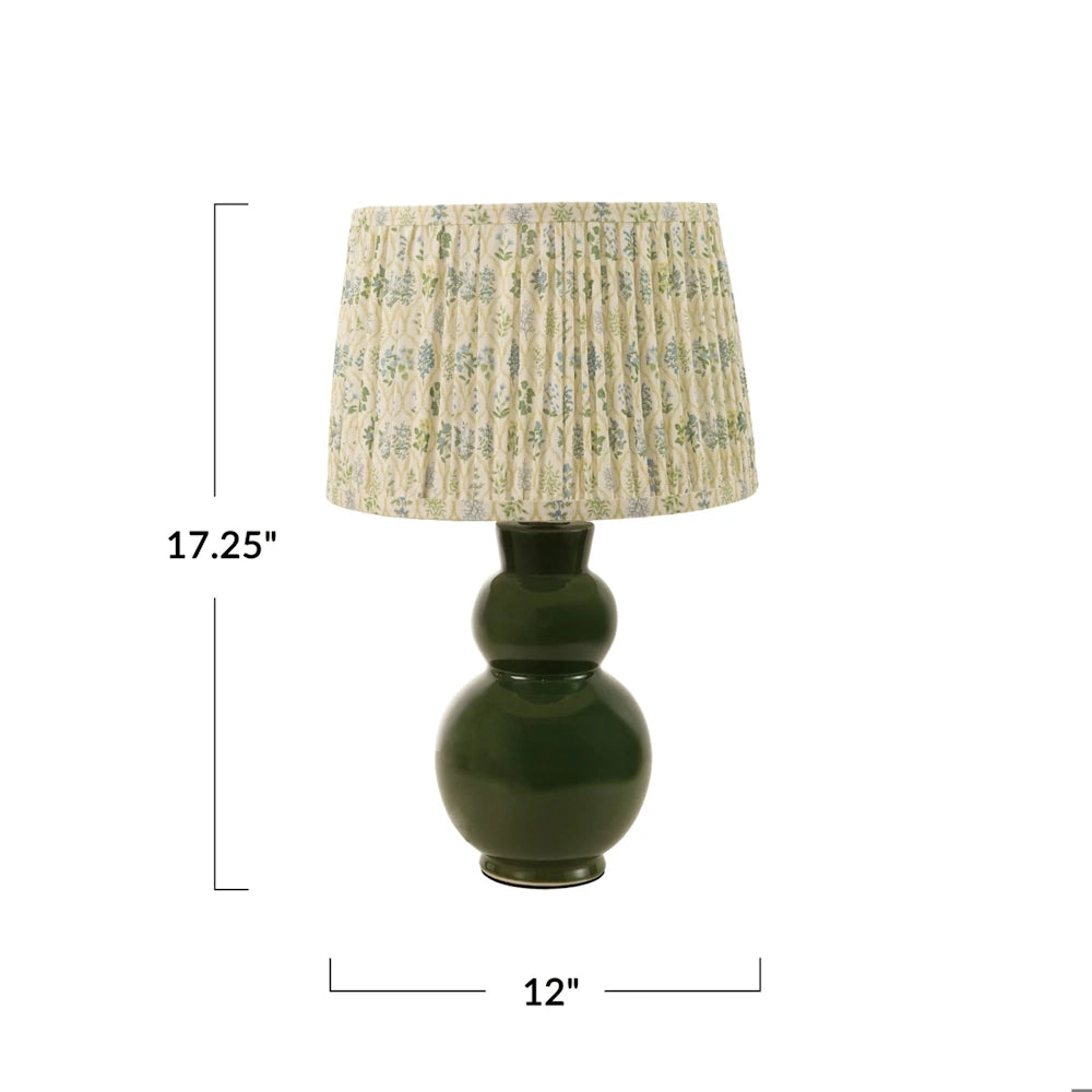 Front view of a dark green glazed stoneware table lamp with a pleated floral fabric shade showing dimensions of 17.25 inches high and 12 inches wide.