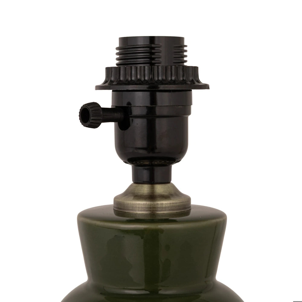 Close-up front view of the black socket and rotary switch on a dark green stoneware table lamp base.
