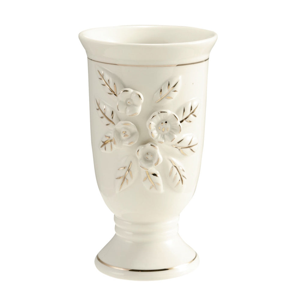 White stoneware footed vase with embossed floral design and gold accents.