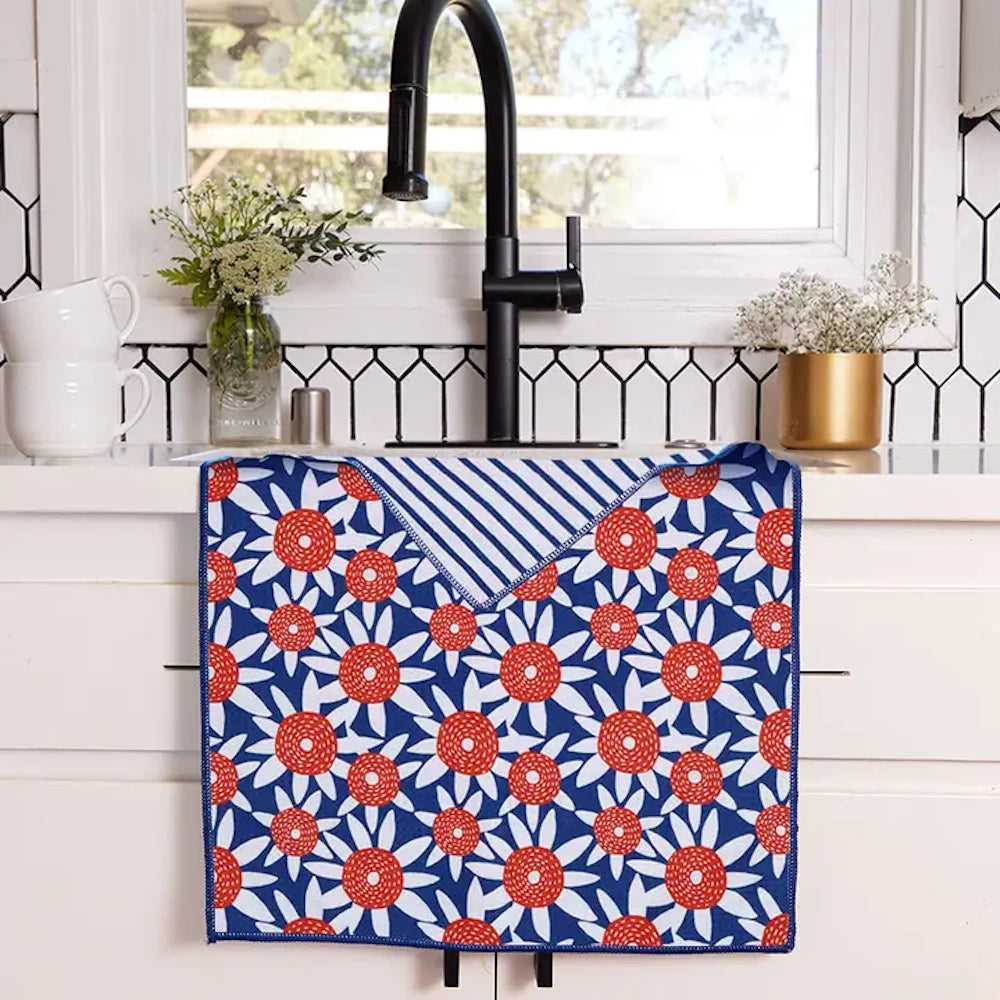Red sunflower tea towel with blue and white stripes draped over a kitchen sink, featuring a modern floral pattern.