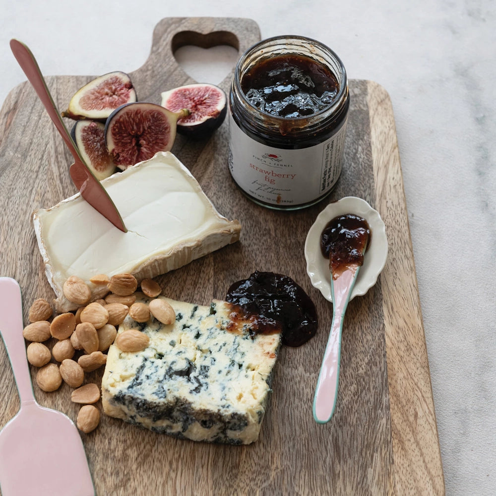 Strawberry fig preserves on a cheese board with brie, blue cheese, fresh figs, and almonds.