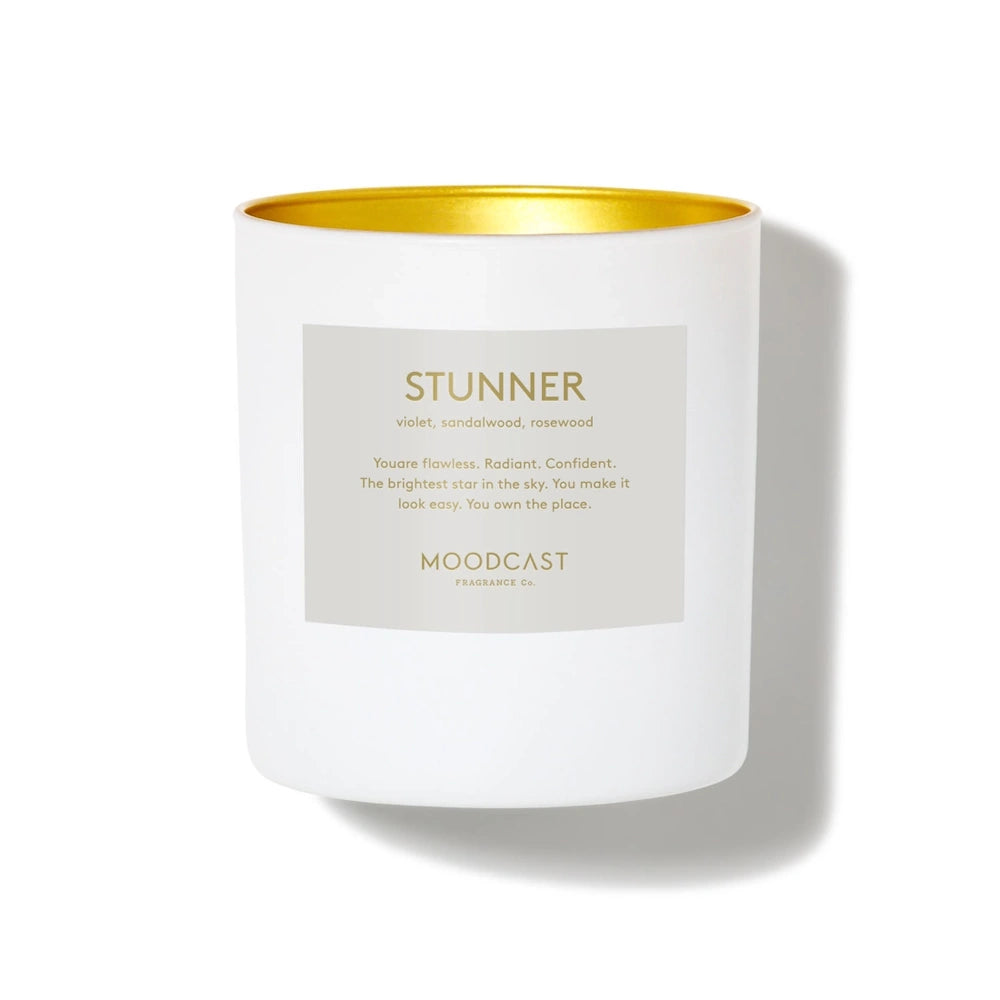 Moodcast Stunner candle in a white jar with gold interior rim and off-white label.